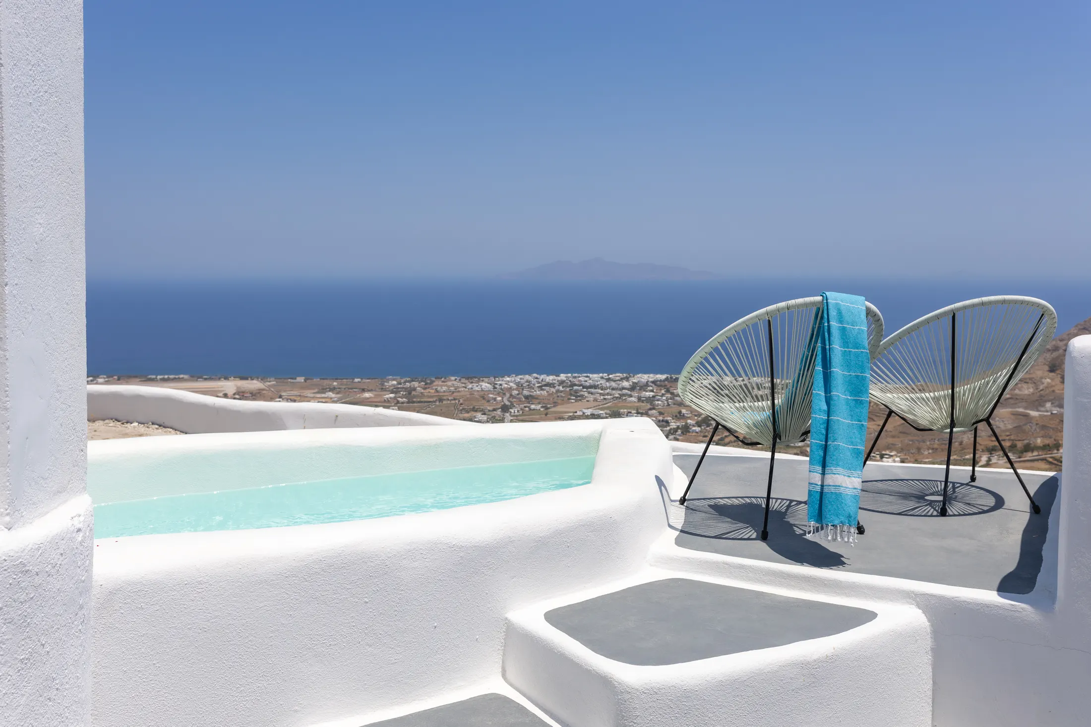 Assyrtiko suite — private pool on a whitewashed terrace, with two chairs looking out over the village to the sea
