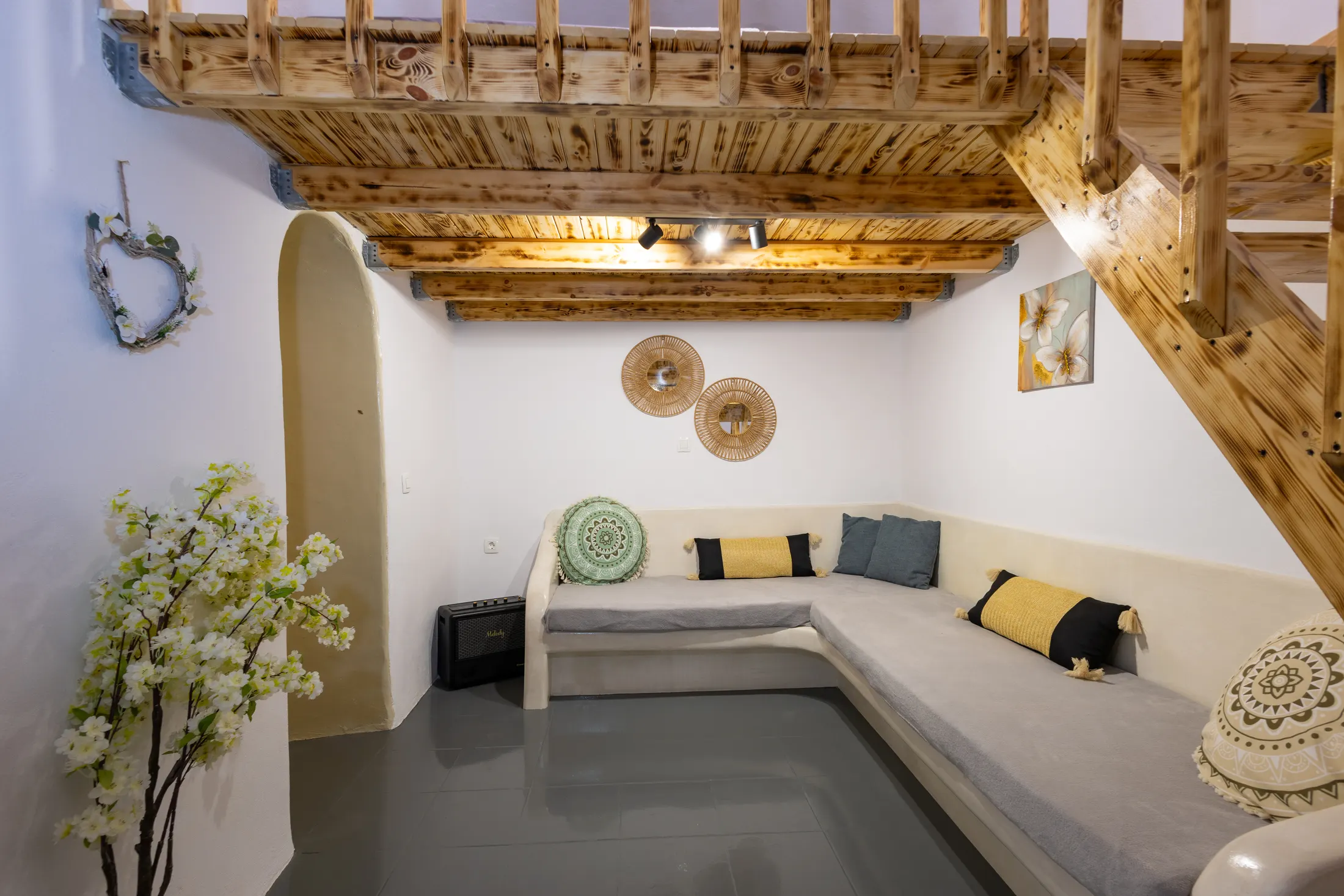 Mandilaria suite — living room with a corner sofa beneath a timber-beamed ceiling