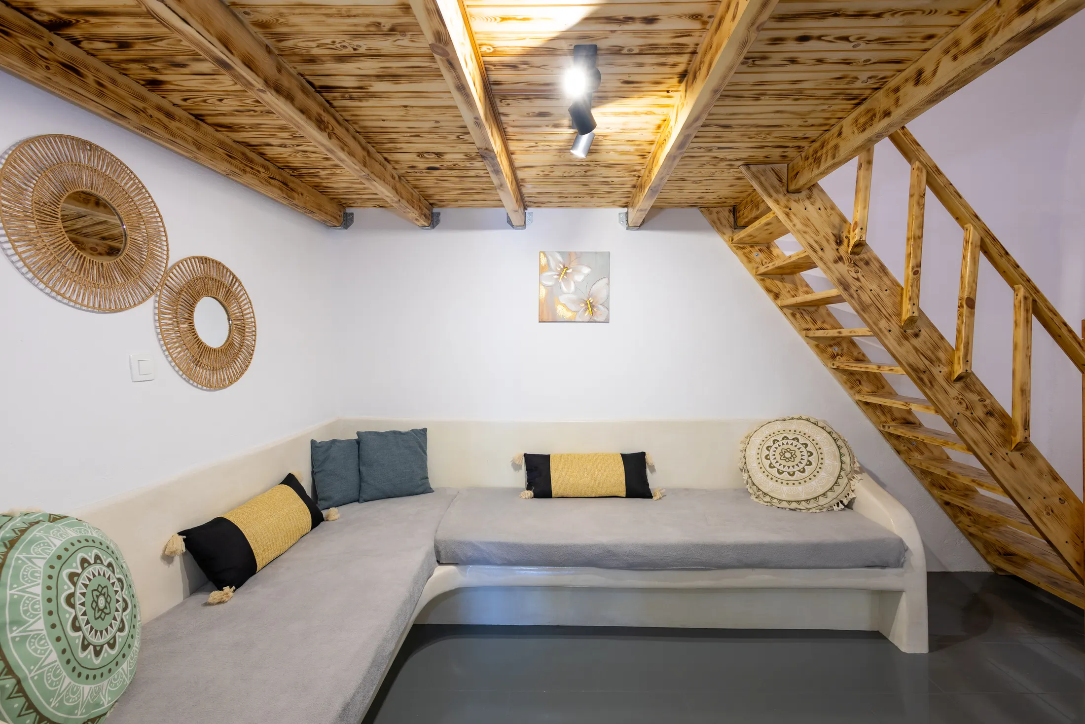 Mandilaria suite — living room with a corner sofa beneath a timber-beamed ceiling